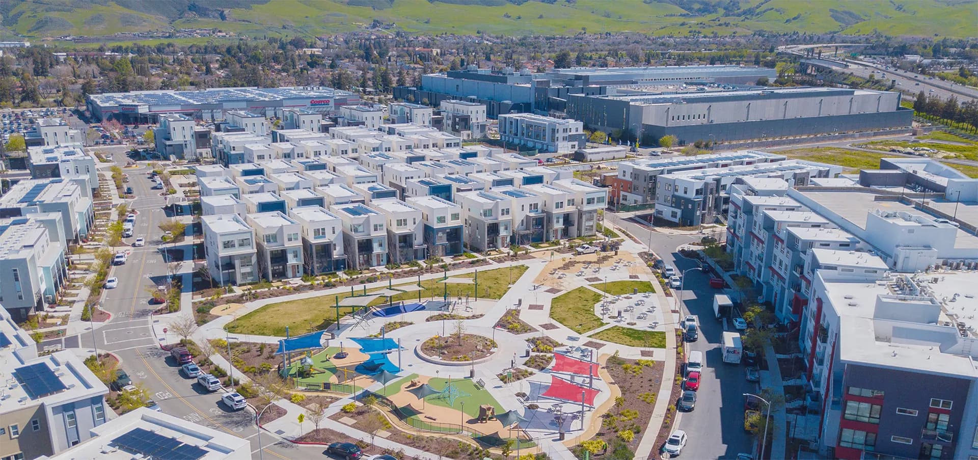 Aerial view of Urban Oaks in South San Jose, with modern townhomes around a central park and playground and the Santa Teresa Hills behind